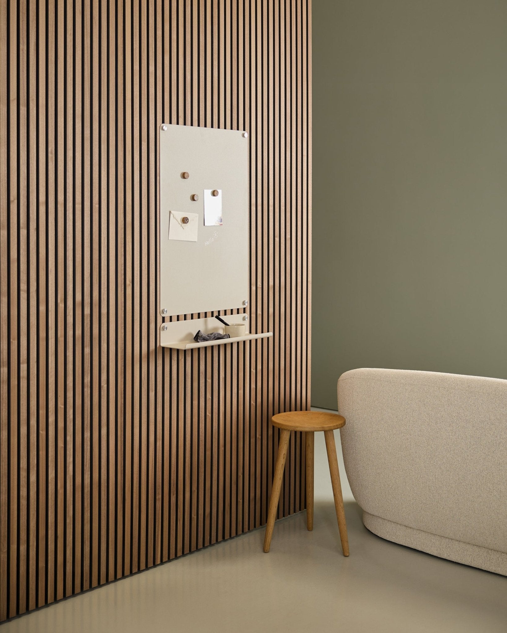 Interior minimalista com sofá beige e banco de madeira, com um quadro magnético WoodUpp Norr large beige montado num painel acústico de madeira Akupanel de estilo nórdico junto a uma parede verde.